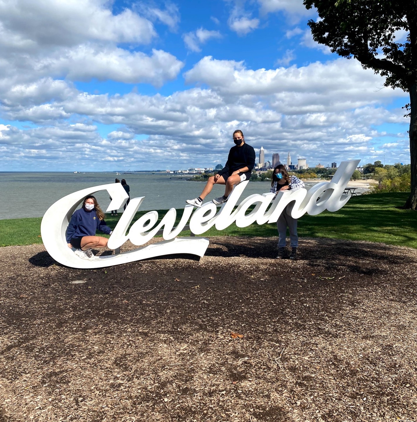 Three students sitting on sculpture-esque sign for Cleveland