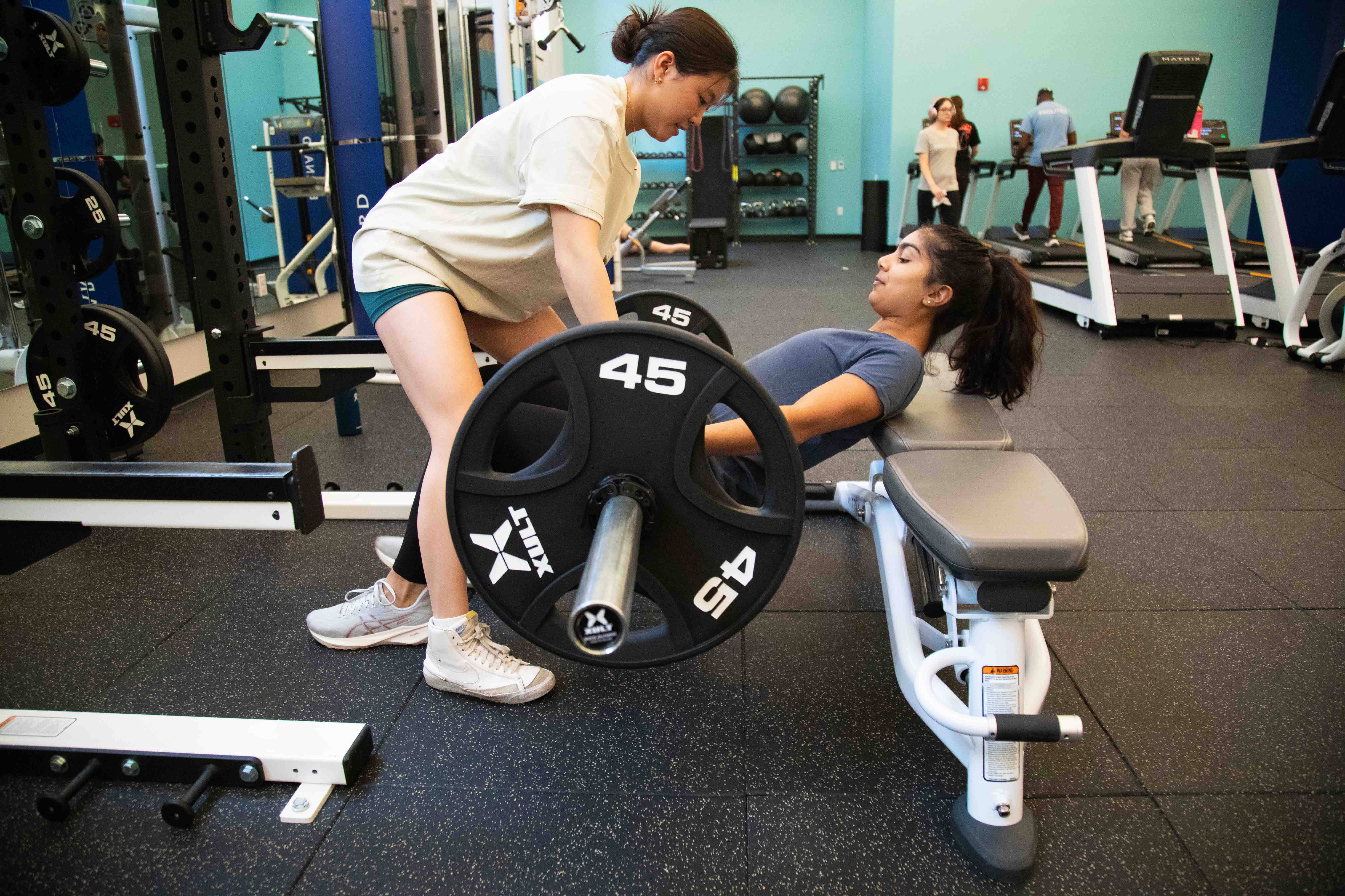Two women in a gym working with a weight